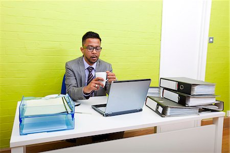 simsearch:693-03474486,k - Portrait of Indian Businessman holding mug and working on his laptop computer at his desk Foto de stock - Sin royalties Premium, Código: 693-06967515