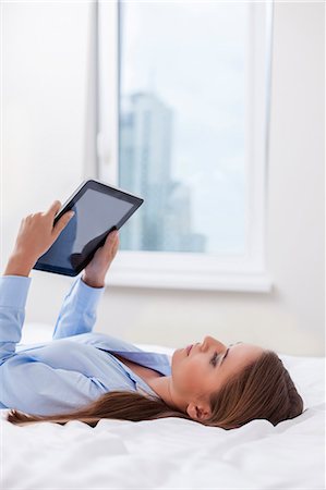 Beautiful woman using tablet computer on her bed Stock Photo - Premium Royalty-Free, Code: 693-07444424