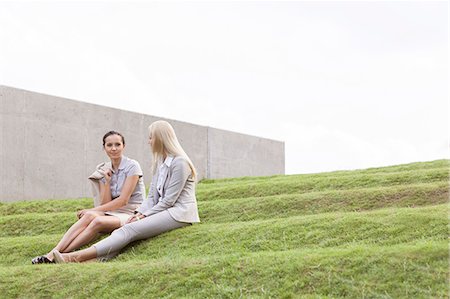 personal - Full length of businesswomen sitting on grass steps against sky Stockbilder - Premium RF Lizenzfrei, Bildnummer: 693-07444458