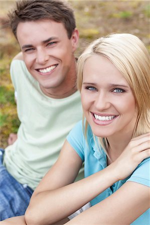 Portrait of smiling young woman with man relaxing in park Stock Photo - Premium Royalty-Free, Code: 693-07444487