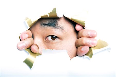 Young Korean man looking through ripped paper hole Stock Photo - Premium Royalty-Free, Code: 693-07444526
