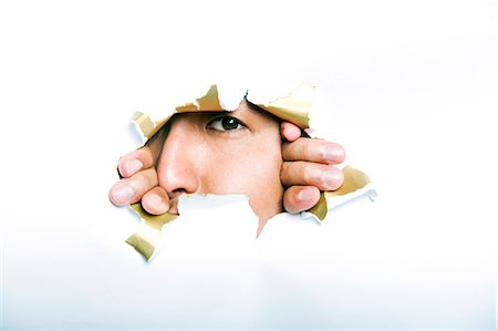 Young Korean man looking through ripped paper hole Stock Photo - Premium Royalty-Free, Code: 693-07444527