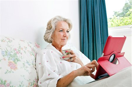 Senior woman using digital tablet while having coffee on bed at home Foto de stock - Sin royalties Premium, Código: 693-07444520