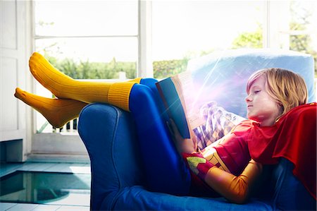 Little boy dressed as a super hero reading a book Stock Photo - Premium Royalty-Free, Code: 693-07444553