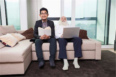 Portrait of grandson reading book while grandfather using laptop on sofa at home Stock Photo - Premium Royalty-Free, Code: 693-07455842