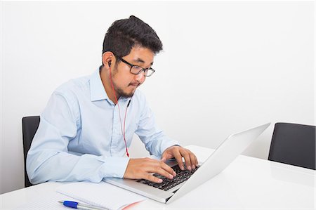 simsearch:693-07455974,k - Young businessman listening music while using laptop in office Stockbilder - Premium RF Lizenzfrei, Bildnummer: 693-07455851