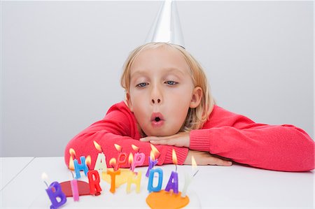 delicious food table pictures white - Girl blowing birthday candles at table in house Stock Photo - Premium Royalty-Free, Code: 693-07455862