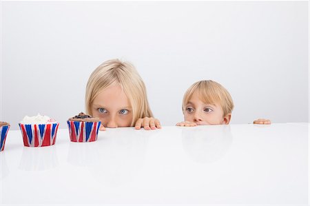 Brother and sister staring at cupcakes on table Photographie de stock - Premium Libres de Droits, Code: 693-07455887