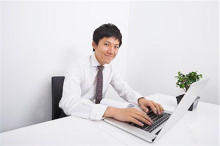 desk with computer - Portrait of confident mid adult businessman using laptop at office desk Stock Photo - Premium Royalty-Free, Code: 693-07455895