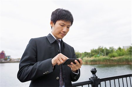 simsearch:693-07455915,k - Mid adult Asian businessman using cell phone along river Photographie de stock - Premium Libres de Droits, Code: 693-07455893