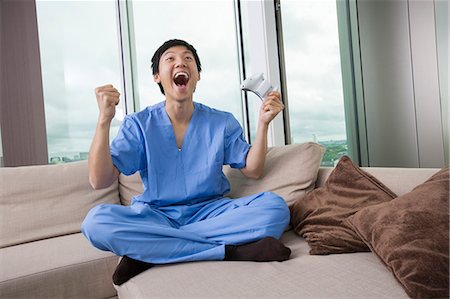 Full length of excited mid adult man playing video game in living room Stock Photo - Premium Royalty-Free, Code: 693-07455916