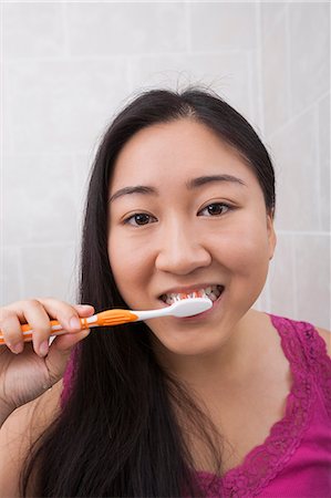 Close-up view of young Asian woman brushing her teeth in bathroom Photographie de stock - Premium Libres de Droits, Code: 693-07455939