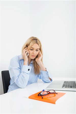 Businesswoman answering smart phone in office Stock Photo - Premium Royalty-Free, Code: 693-07455984