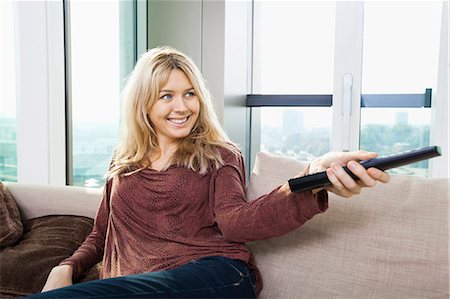 simsearch:693-07456037,k - Smiling young woman watching television on sofa at home Photographie de stock - Premium Libres de Droits, Code: 693-07456010