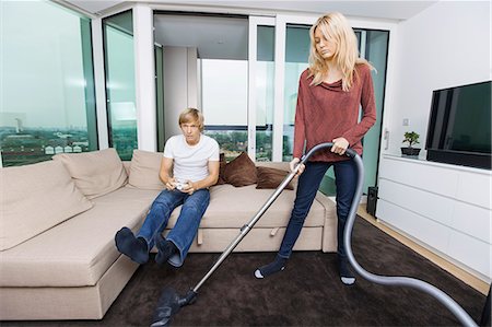 simsearch:693-07456037,k - Woman vacuuming while man play video game in living room at home Photographie de stock - Premium Libres de Droits, Code: 693-07456042