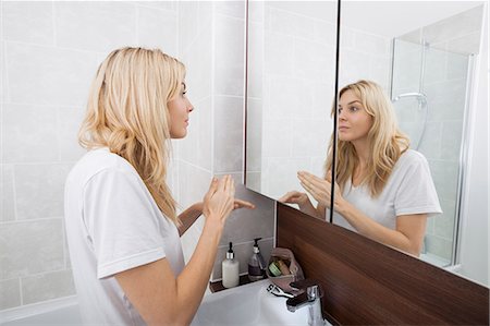 dressing table mirror - Young woman looking at mirror in bathroom Stock Photo - Premium Royalty-Free, Code: 693-07456071