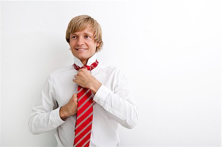 Portrait of mid adult businessman tying tie against white background Foto de stock - Sin royalties Premium, Código: 693-07456086