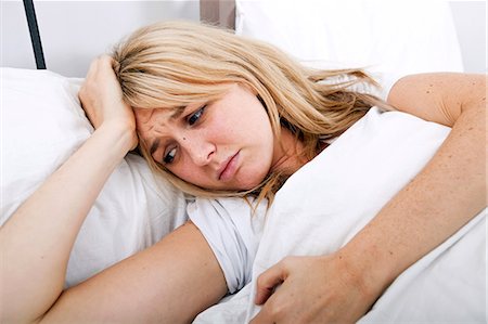 Young woman suffering from headache in bed Photographie de stock - Premium Libres de Droits, Code: 693-07456104