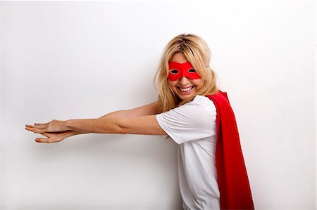 ficción - Side view portrait of happy woman in superhero costume against white background Foto de stock - Sin royalties Premium, Código: 693-07456112