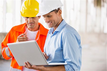 focused professional - Male architects working on laptop at construction site Stock Photo - Premium Royalty-Free, Code: 693-07456125