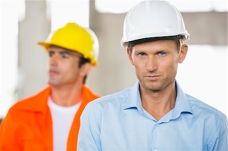 Portrait of confident male architect at construction site with coworker in background Stock Photo - Premium Royalty-Free, Code: 693-07456126