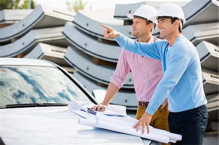 Architects with blueprints on car discussing at site Stock Photo - Premium Royalty-Free, Code: 693-07456138