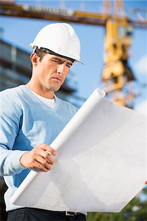 Male architect examining blueprint at construction site Stock Photo - Premium Royalty-Free, Code: 693-07456143