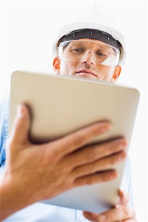Low angle view of male architect using tablet PC against sky Stock Photo - Premium Royalty-Free, Code: 693-07456156