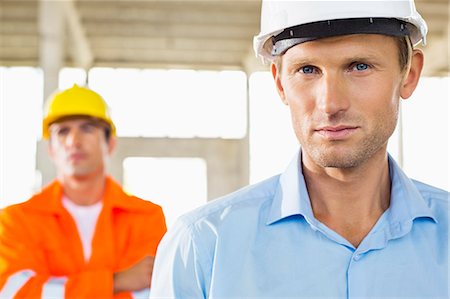 Portrait of confident architect at construction site with coworker in background Stock Photo - Premium Royalty-Free, Code: 693-07456160