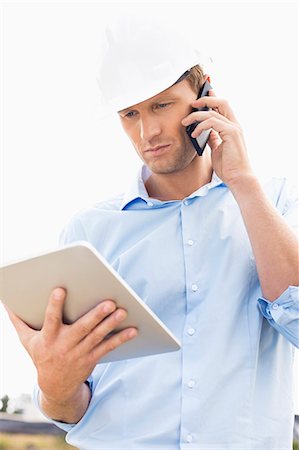 electronics smart phone tablet - Male architect with digital tablet using cell phone at site Stock Photo - Premium Royalty-Free, Code: 693-07456174