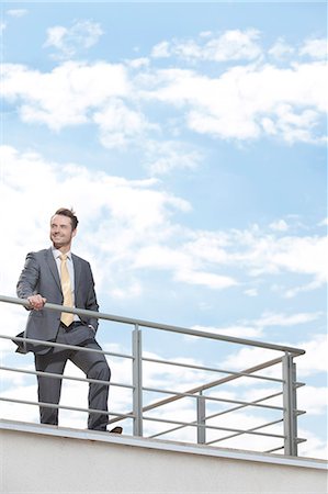 person looking up at sky clouds - Young businessman standing at terrace railings against sky Photographie de stock - Premium Libres de Droits, Code: 693-07456188