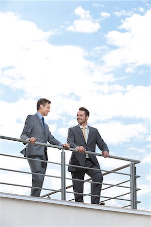 Businessmen standing at terrace railings against sky Stock Photo - Premium Royalty-Free, Code: 693-07456190