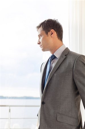 simsearch:693-07456224,k - Pensive businessman standing by glass door in hotel Stock Photo - Premium Royalty-Free, Code: 693-07456210