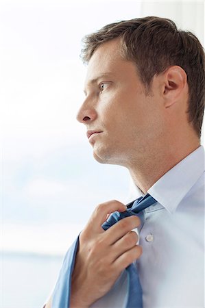Close-up of pensive businessman loosening necktie in hotel Stock Photo - Premium Royalty-Free, Code: 693-07456213