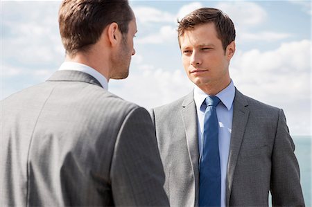 simsearch:693-05552781,k - Businessmen looking at each other against sky Stock Photo - Premium Royalty-Free, Code: 693-07456226