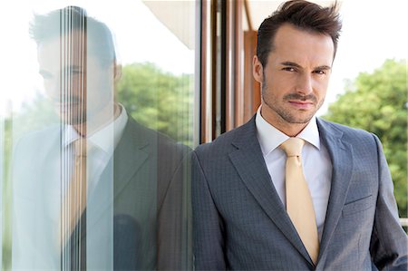 simsearch:693-07672604,k - Portrait of confident businessman leaning on glass door Foto de stock - Sin royalties Premium, Código: 693-07456222