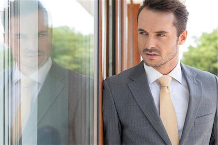 Businessman looking away while leaning on glass door Foto de stock - Sin royalties Premium, Código: 693-07456223