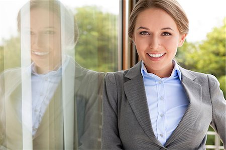 Portrait of happy businesswoman leaning on glass door Foto de stock - Sin royalties Premium, Código: 693-07456230