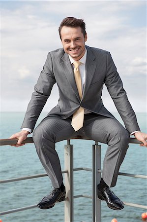 Full-length portrait of happy businessman sitting on terrace railings Foto de stock - Sin royalties Premium, Código: 693-07456233