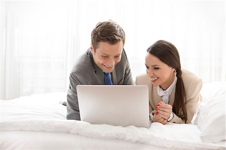 Happy business couple using laptop in hotel room Stock Photo - Premium Royalty-Free, Code: 693-07456250