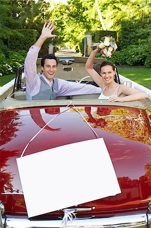 Happy newlyweds waving in convertible with blank sign in foreground Photographie de stock - Premium Libres de Droits, Code: 693-07456330