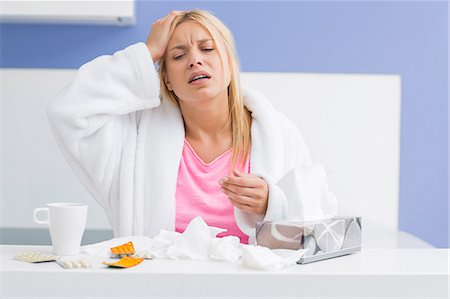 sad woman drink - Young exhausted woman suffering from headache and cold in kitchen Stock Photo - Premium Royalty-Free, Code: 693-07456347