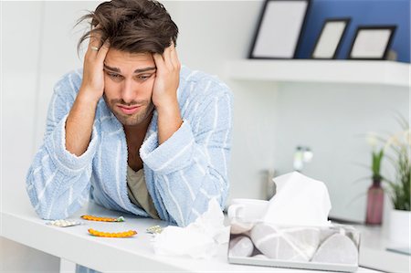 Young ill man suffering from headache at kitchen counter Foto de stock - Sin royalties Premium, Código: 693-07456343