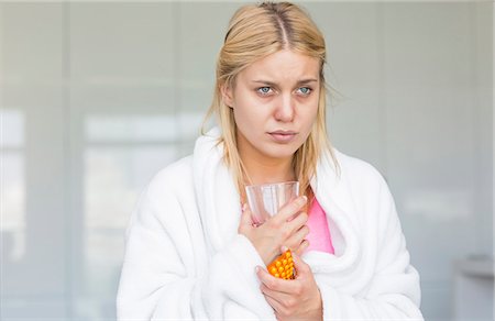 soufre - Young woman holding medicine and glass of water while suffering from cold Foto de stock - Sin royalties Premium, Código: 693-07456354