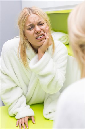 Young woman suffering from toothache while looking at mirror Stock Photo - Premium Royalty-Free, Code: 693-07456368
