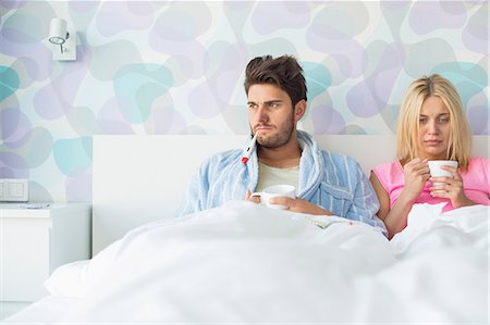 sad woman drink - Young couple suffering from cold while relaxing in bed at home Stock Photo - Premium Royalty-Free, Code: 693-07456385