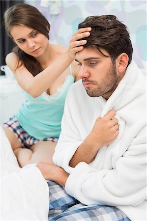 sick man - Young woman checking man's temperature on bed Stock Photo - Premium Royalty-Free, Code: 693-07456389