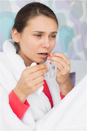 Young woman taking medicine in bedroom at home Photographie de stock - Premium Libres de Droits, Code: 693-07456397