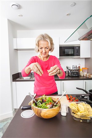 Senior woman preparing salad at kitchen counter Foto de stock - Sin royalties Premium, Código: 693-07456444