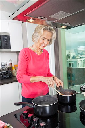 domestic - Smiling senior woman preparing food at kitchen counter Stock Photo - Premium Royalty-Free, Code: 693-07456446
